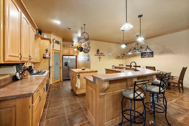 kitchen with a center island with sink, visible vents, appliances with stainless steel finishes, ornamental molding, and a sink