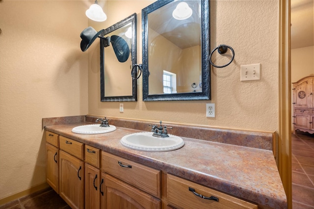 full bathroom with a textured wall, tile patterned floors, a sink, and double vanity