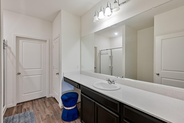 bathroom featuring a shower stall, wood finished floors, and vanity