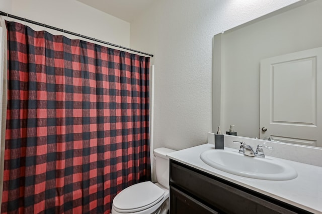 bathroom with toilet, a textured wall, a shower with shower curtain, and vanity