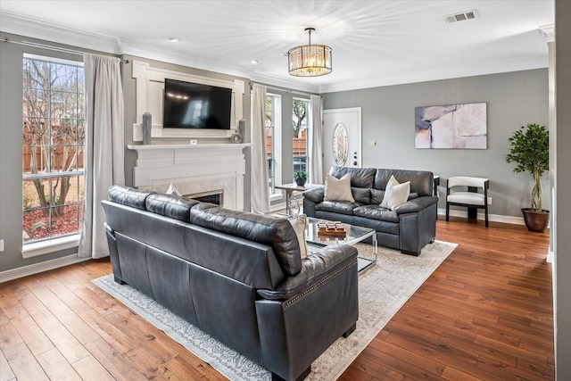 living area with a wealth of natural light, visible vents, crown molding, and hardwood / wood-style flooring