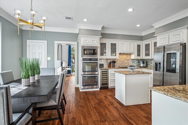 kitchen featuring beverage cooler, visible vents, stainless steel appliances, decorative backsplash, and a center island