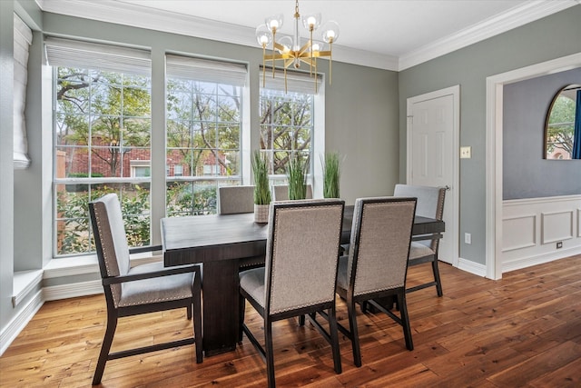 dining room featuring a healthy amount of sunlight, an inviting chandelier, ornamental molding, and hardwood / wood-style flooring