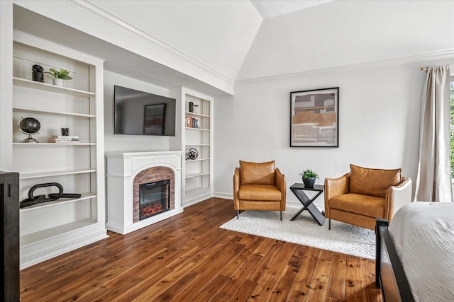 living area featuring built in shelves, ornamental molding, dark wood-style floors, a glass covered fireplace, and lofted ceiling