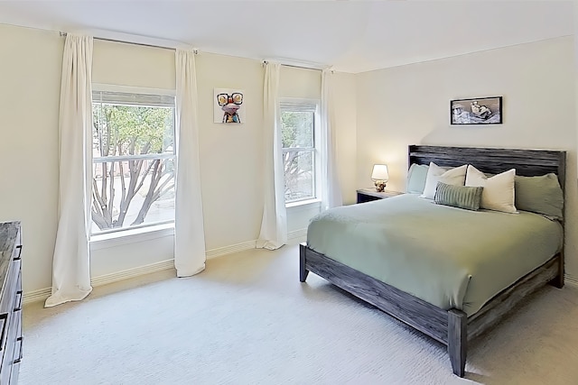 bedroom featuring multiple windows, baseboards, and light carpet