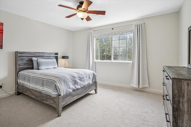 bedroom featuring light colored carpet, a ceiling fan, and baseboards