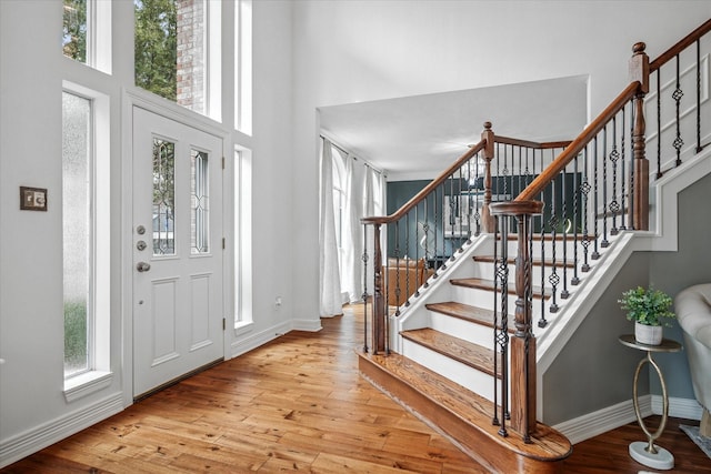 foyer entrance with hardwood / wood-style floors, a high ceiling, stairs, and baseboards