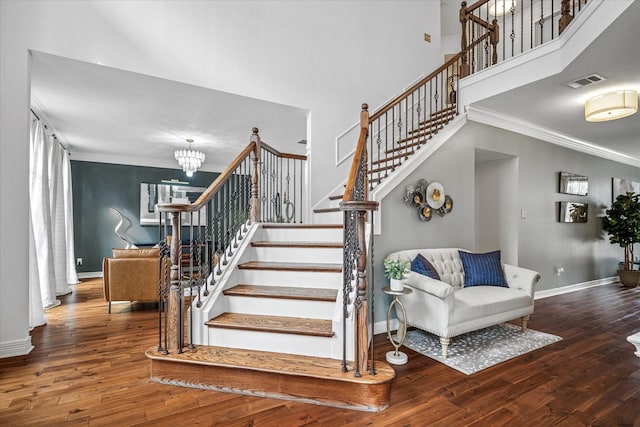 stairs featuring hardwood / wood-style floors, crown molding, baseboards, and visible vents