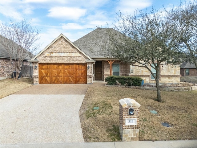 view of front facade with a garage, driveway, roof with shingles, and brick siding