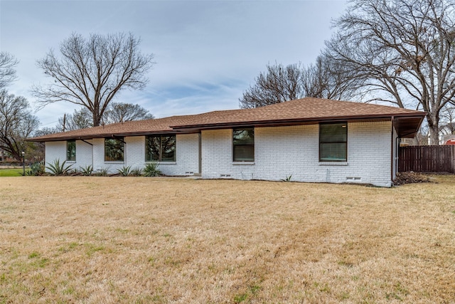 view of front of property featuring brick siding, roof with shingles, crawl space, fence, and a front lawn