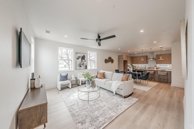 living area featuring light wood-style flooring, a ceiling fan, visible vents, and recessed lighting