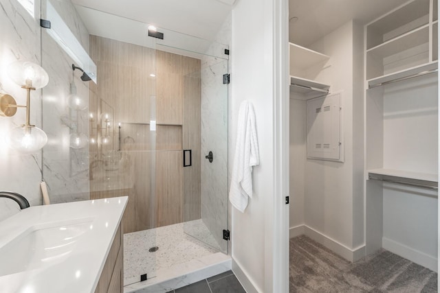 full bathroom with baseboards, a sink, a spacious closet, and a marble finish shower