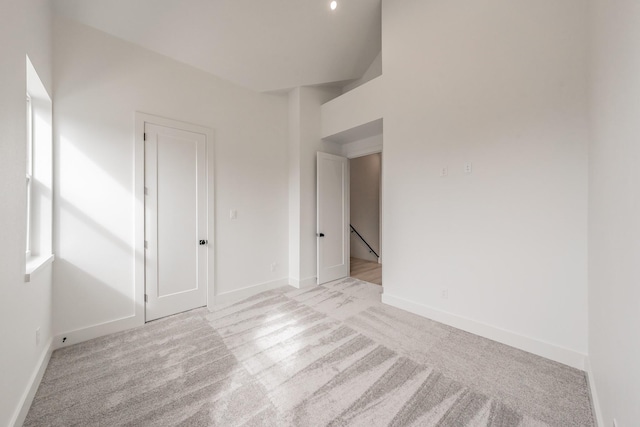 unfurnished room featuring light colored carpet and baseboards