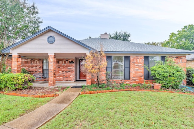 single story home with a shingled roof, a front yard, brick siding, and a chimney