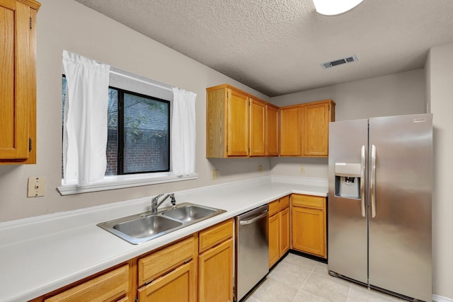 kitchen with a textured ceiling, a sink, visible vents, light countertops, and appliances with stainless steel finishes