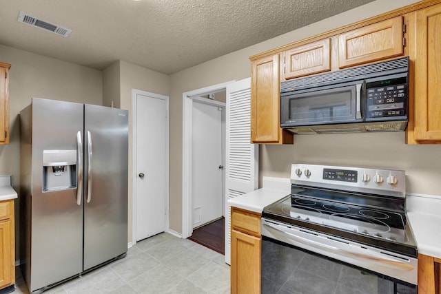 kitchen featuring a textured ceiling, light countertops, appliances with stainless steel finishes, and visible vents