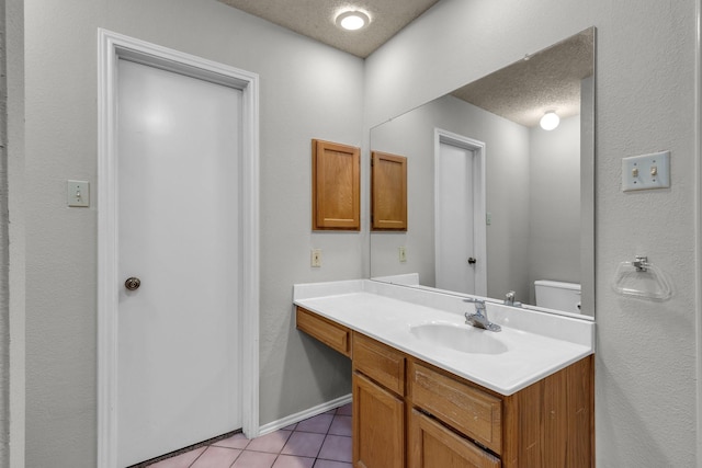 bathroom with a textured ceiling, toilet, vanity, baseboards, and tile patterned floors