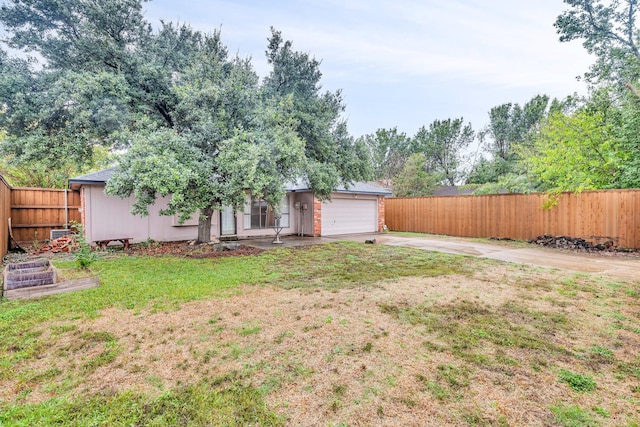 view of yard with concrete driveway, an attached garage, and fence