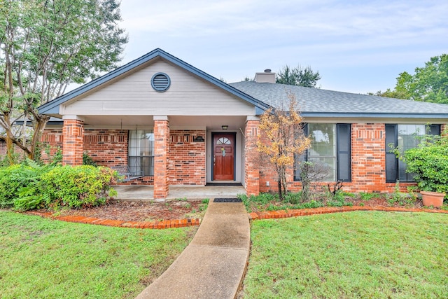 ranch-style home featuring a shingled roof, brick siding, a chimney, and a front lawn