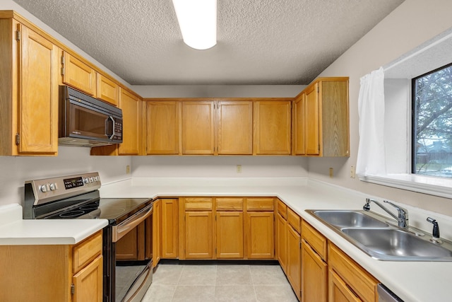 kitchen with light tile patterned floors, light countertops, appliances with stainless steel finishes, a sink, and a textured ceiling