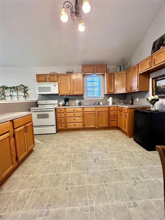 12900 Fm 121, Van Alstyne, TX 75495 - kitchen featuring lofted ceiling, white appliances, a sink, light countertops, and brown cabinetry