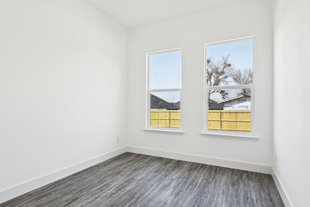 spare room featuring baseboards and dark wood finished floors