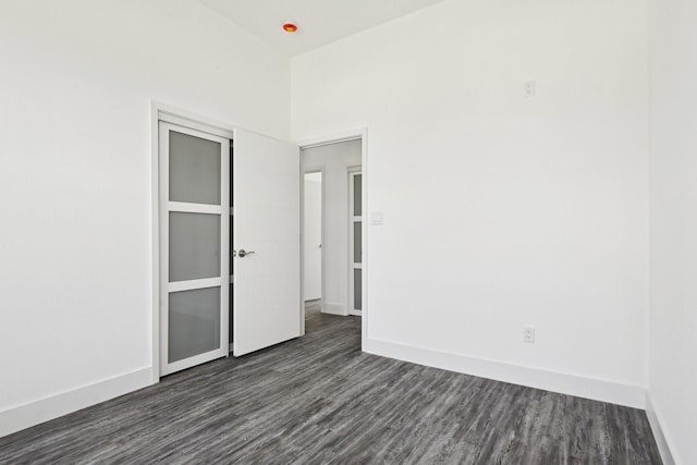 spare room featuring dark wood-style floors and baseboards