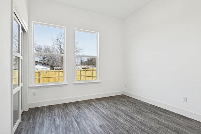 unfurnished room with dark wood-type flooring and baseboards