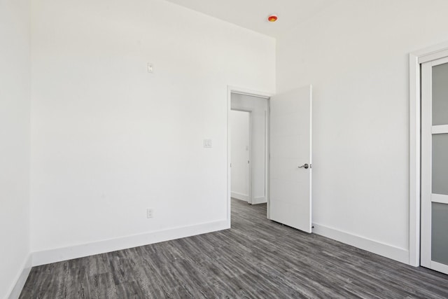 unfurnished bedroom with a closet, baseboards, and dark wood-type flooring