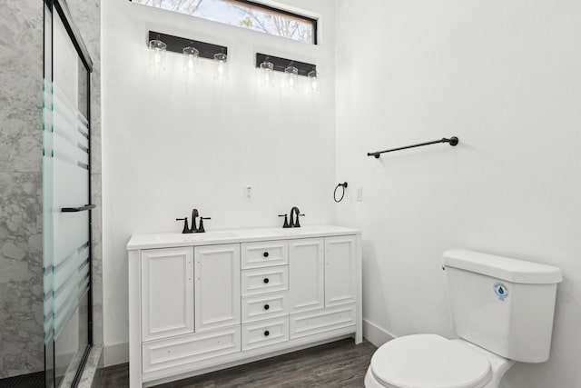 bathroom with a stall shower, a sink, toilet, and wood finished floors