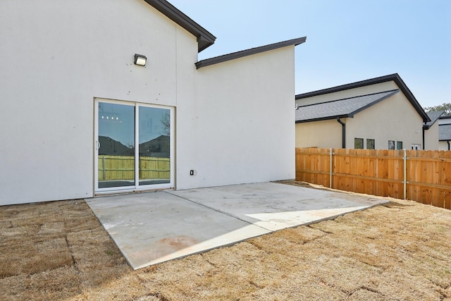 back of house with fence, a patio, and stucco siding