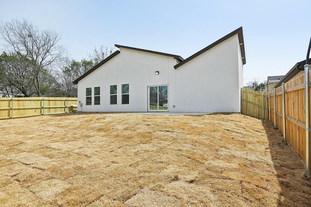 rear view of property featuring a fenced backyard and stucco siding