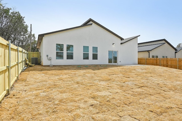 rear view of property featuring central AC, a fenced backyard, and stucco siding