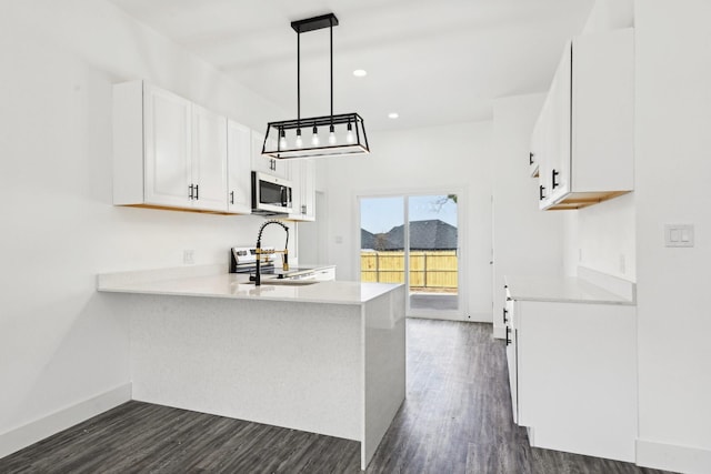 kitchen featuring stainless steel appliances, dark wood-style flooring, light countertops, and a peninsula