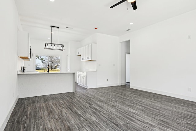 unfurnished living room featuring baseboards, visible vents, dark wood finished floors, ceiling fan, and a sink