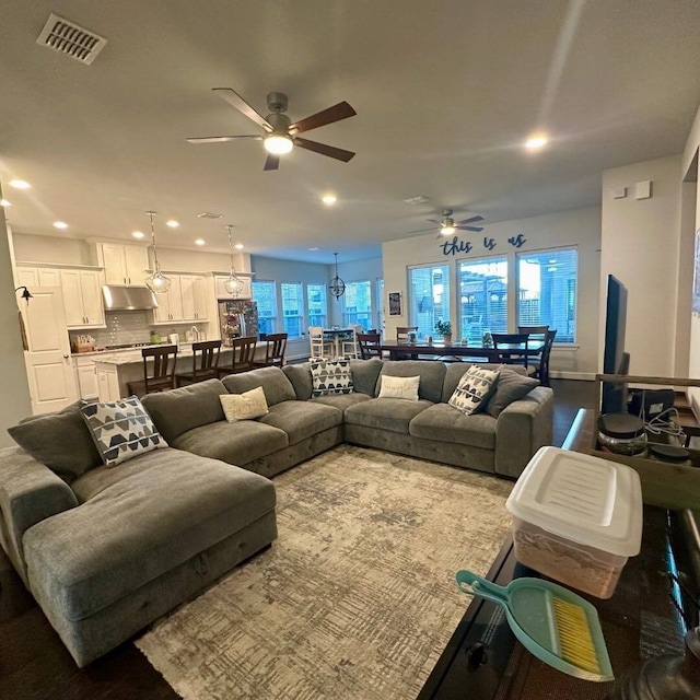 living area with a ceiling fan, recessed lighting, and visible vents