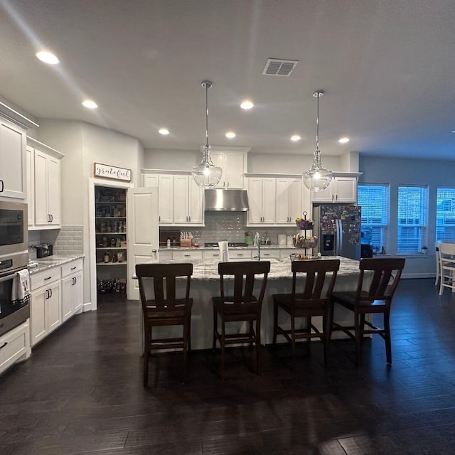 kitchen featuring stainless steel appliances, white cabinetry, visible vents, and under cabinet range hood