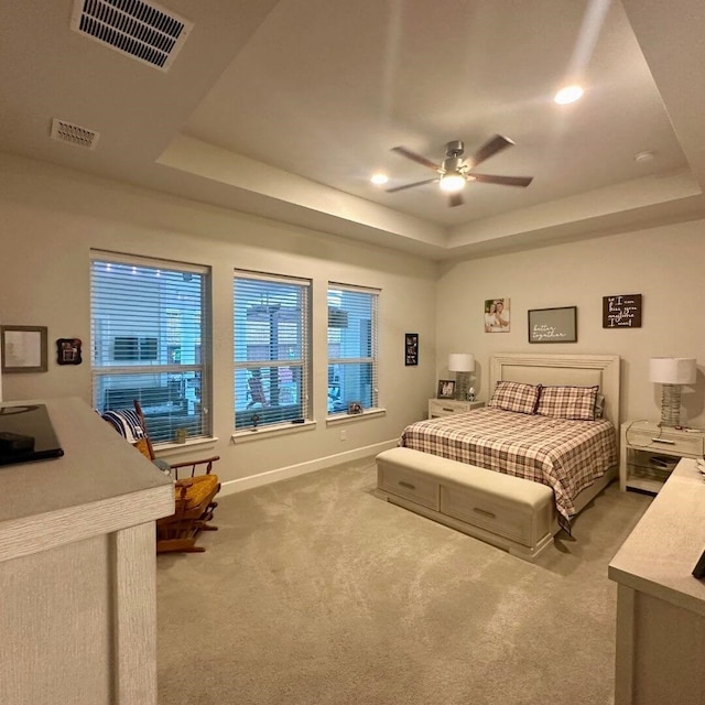 carpeted bedroom featuring ceiling fan, a raised ceiling, visible vents, and baseboards