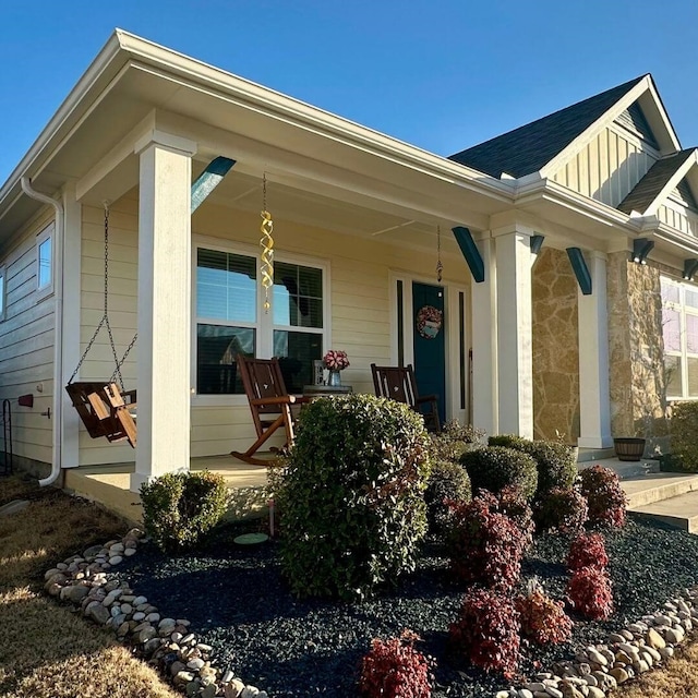 exterior space featuring covered porch, stone siding, and board and batten siding