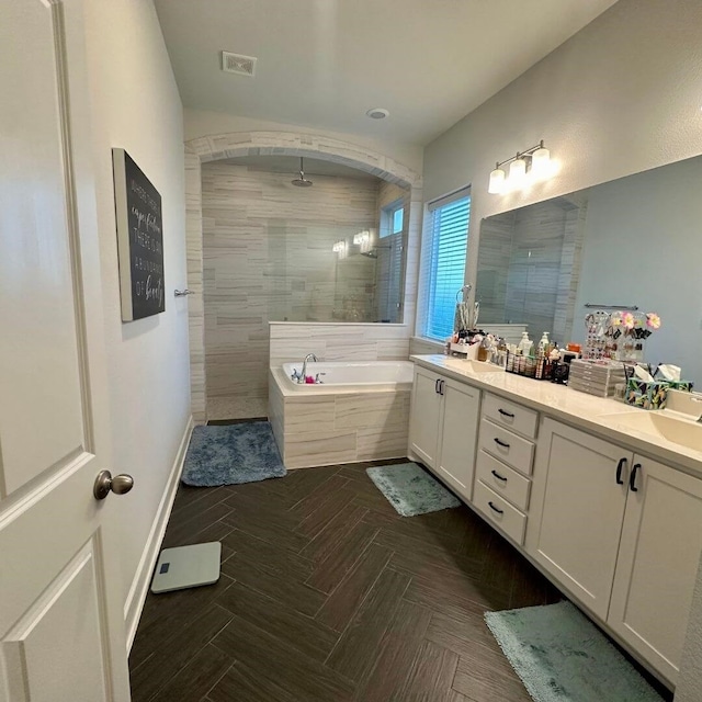 bathroom featuring double vanity, visible vents, a garden tub, a tile shower, and a sink