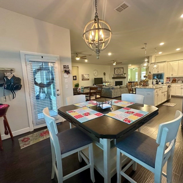 dining space with baseboards, visible vents, a ceiling fan, dark wood-type flooring, and a fireplace