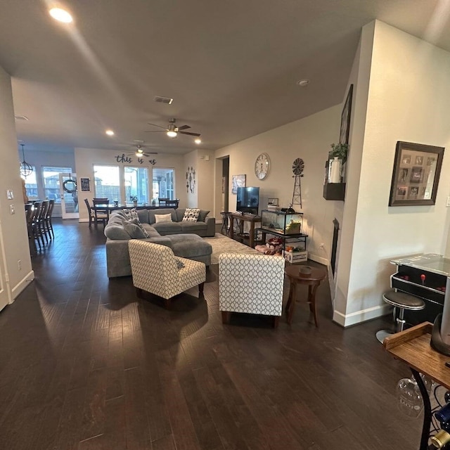 living area featuring a ceiling fan, wood finished floors, visible vents, and baseboards