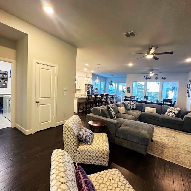 living room with a ceiling fan, baseboards, visible vents, and dark wood-style flooring