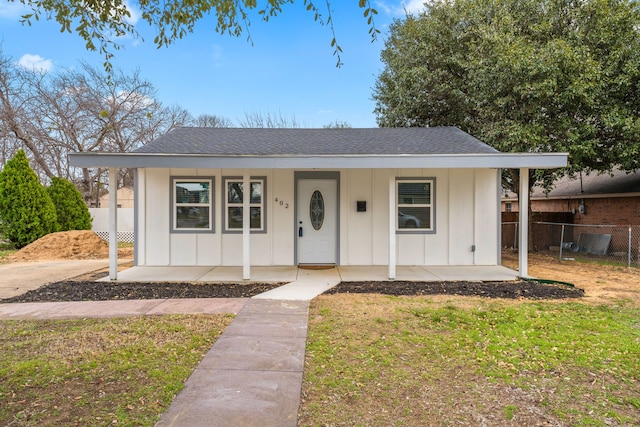 bungalow-style home featuring a shingled roof, fence, a porch, and board and batten siding