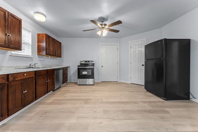 kitchen with light wood finished floors, light countertops, appliances with stainless steel finishes, a sink, and dark brown cabinets