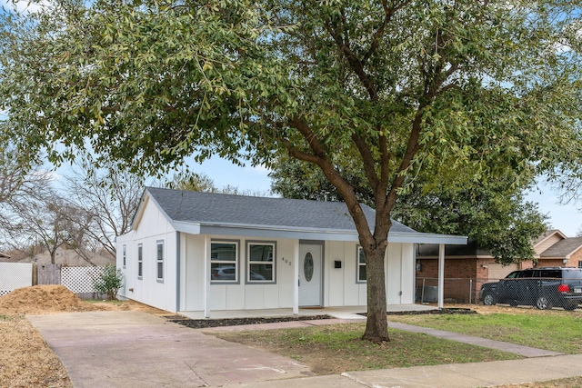 view of front of property featuring roof with shingles, a porch, board and batten siding, and fence