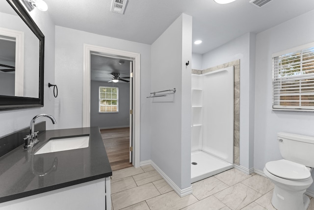 bathroom with visible vents, toilet, vanity, a walk in shower, and baseboards