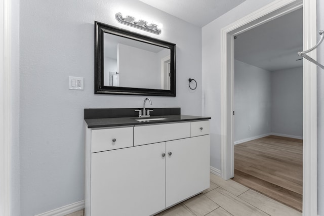 bathroom featuring wood finished floors, vanity, and baseboards