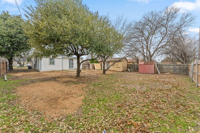 view of yard with a fenced backyard, a storage unit, and an outbuilding