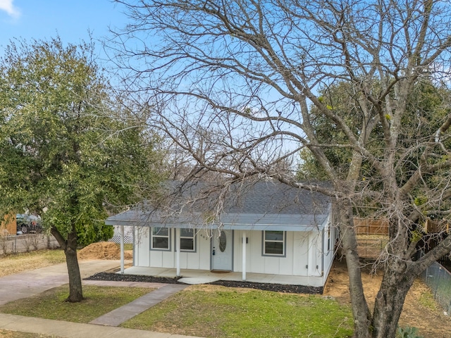 view of front of property featuring a porch, board and batten siding, fence, driveway, and a front lawn